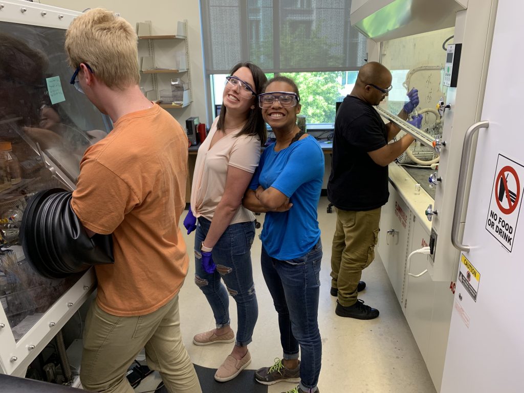 Research students are posing with big smiles in the lab.