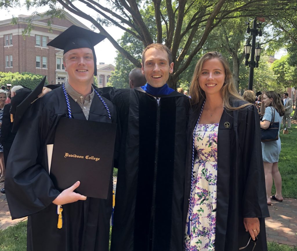 Nick Kennedy ('19) and Jennie Goodell ('19) standing with Mitch on the lawn after graduation.