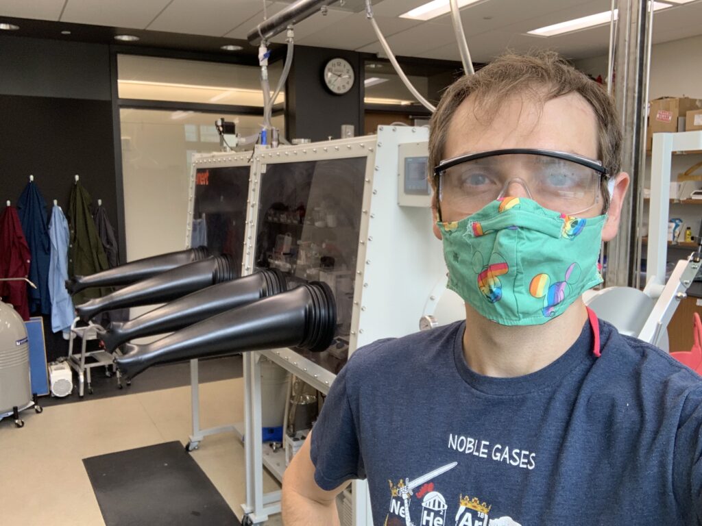 Person standing in a laboratory with safety goggles and a Disney-themed face mask for COVID-19 safety.